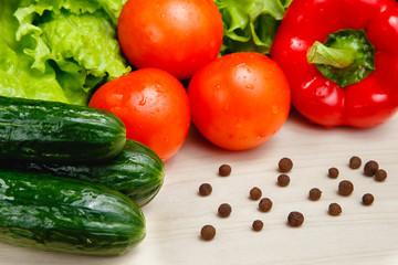 Fresh vegetables on the table: red pepper, lettuce, cucumber, tomatoes, sweet pepper peas. Cutting board