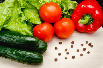 Fresh vegetables on the table: red pepper, lettuce, cucumber, tomatoes, sweet pepper peas. Cutting board