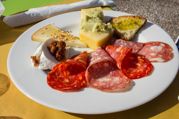 Antipasto di montagna con vari tipi di salami, polenta con purea di fave, bruschetta con olio extravergine di oliva, varie tipologie di formaggi e patè di pomodori secchi