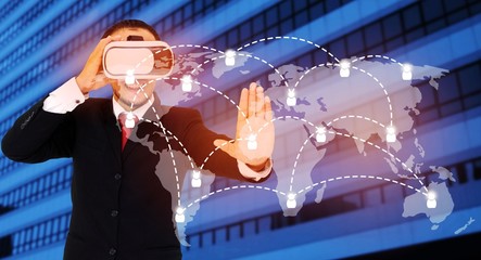 asian businessman wearing VR virtual reality headset, business and technology concept for future with world map social media connection on blurred building background color tone effect wide screen