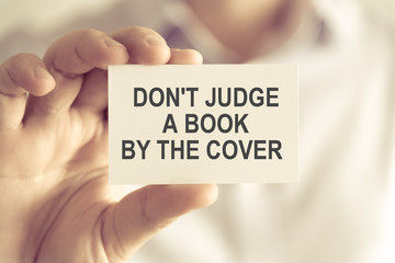 Businessman holding DONT JUDGE A BOOK BY THE COVER message card