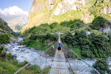 Woman backpacker crossing suspension bridge in Himalayas Nepal