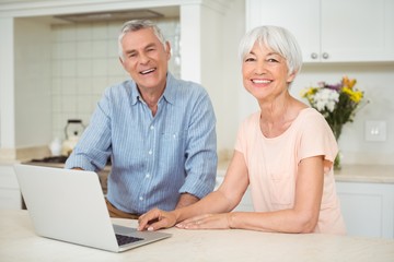 Portrait of senior couple using laptop in kitchen