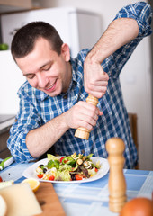 man adding spice to the salad