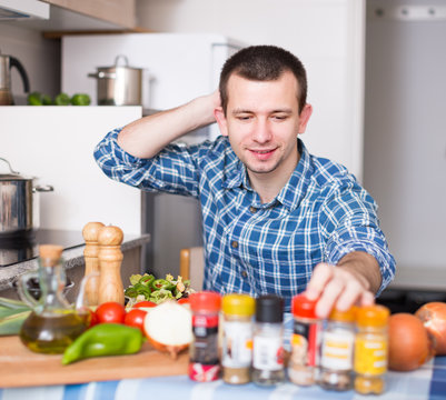 male chooses spices in kitchen at home