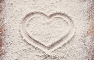 Baking concept on wood background, sprinkled flour with heart, copy space