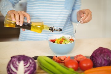Woman pouring oil in to a bowl of vegetable salad - Powered by Adobe