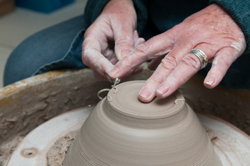 Pottery making with womans hands working at the pottery wheel