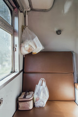 Fototapeta na wymiar Thai Train Seat that near the Window with Food in Plastic Bags and Fabric Bags. 
