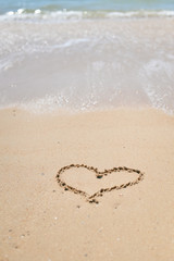 Love heart sign on the wet beach sand sea wave background