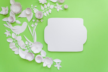 frame with white paper flowers on green background. Cut from paper.