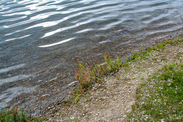 close up of lake showing ripples in the water and gravel shore
