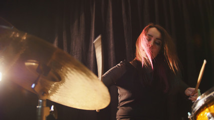 Flowing black hair - beauty girl plays drum rock at garage