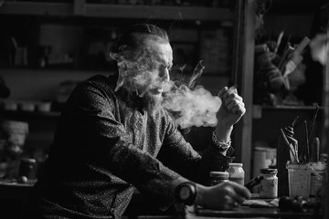 Obraz premium Man portrait smoking an electronic cigarette in art studio