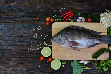Fresh fish with aromatic herbs, spices, salt with lemon with chopping board