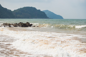 Waves on the beach with mountain background.