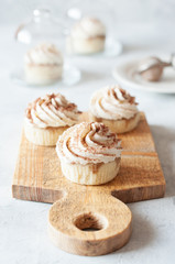 Cupcakes with whipped cream on wooden board