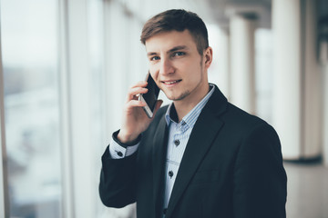 Businessman talk to cellphone and look on camera in office