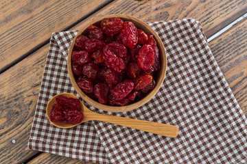 Closeup Sun-dried cocktail tomatoes in wooden spoon and cup on wooden table.