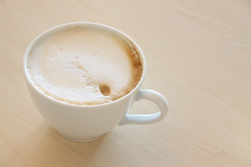 Latte coffee on light wooden table.