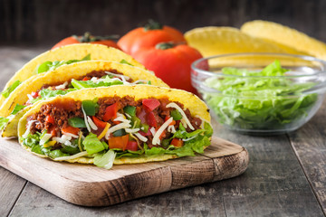 Traditional Mexican tacos with meat and vegetables on wooden background
