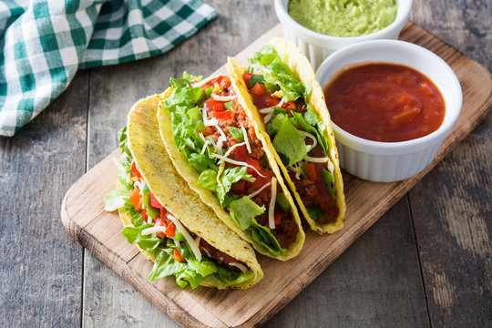 Traditional Mexican tacos with meat and vegetables on wooden background
