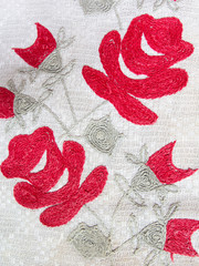 Handmade embroidery in the old style of red flowers on a woven fabric