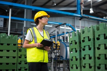 Female factory worker maintaining record on digital tablet