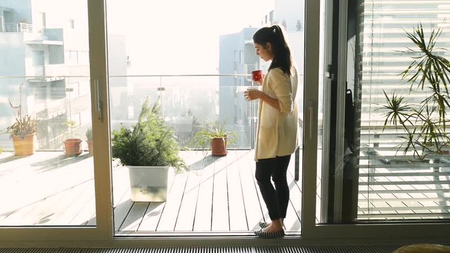Woman relaxing on balcony holding cup , drinking coffee or tea
