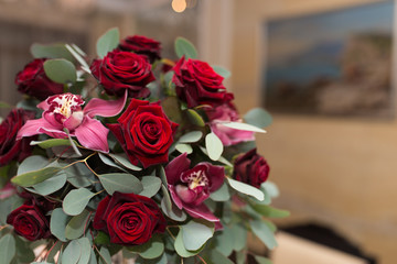 Wedding arrangement with fresh red roses, orchids and eucalyptus on the banquet table