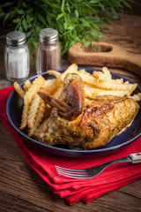 Roasted chicken with french fries on a plate.