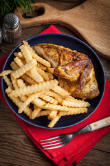Roasted chicken with french fries on a plate.