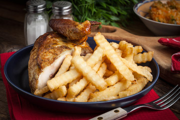 Roasted chicken with french fries on a plate.