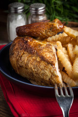 Roasted chicken with french fries on a plate.