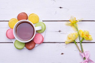 A cup of hot tea and krasochnochnoe macaroons on a wooden table.