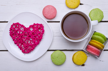 A cup of hot tea and krasochnochnoe macaroons on a wooden table.