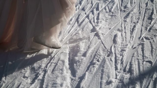 Woman in long dress and silver shoes walking at winter sunny day