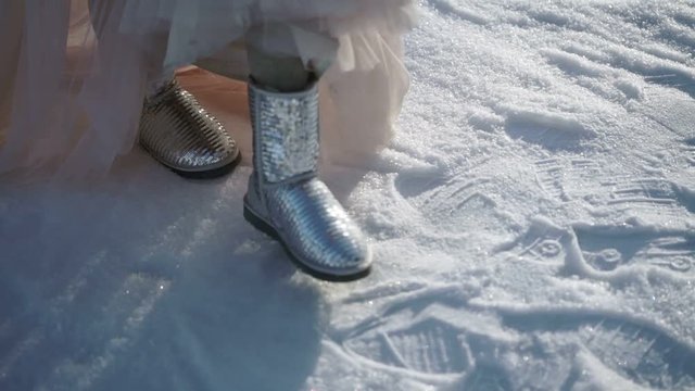Woman in long dress and silver shoes walking at winter sunny day