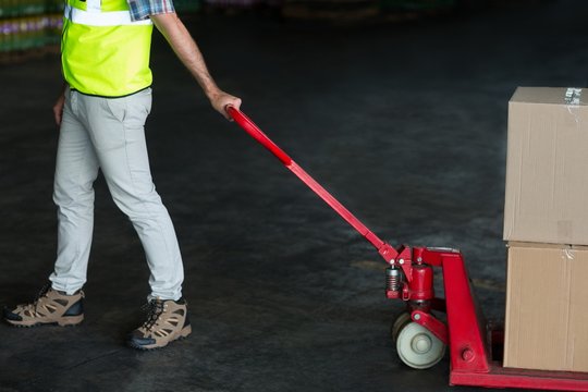 Factory worker pulling trolley of cardboard boxes