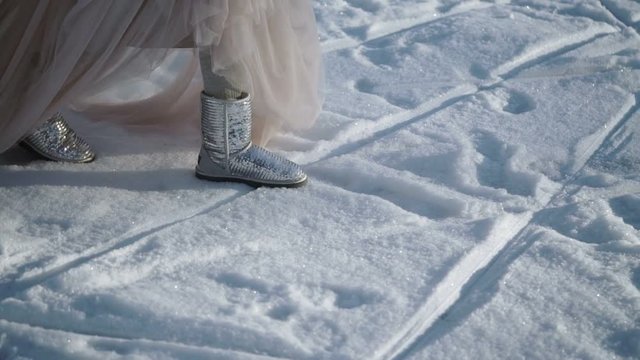 Woman in long dress and silver shoes walking at winter sunny day