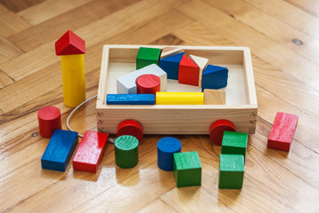 Children wooden trolley with colorful wooden cubes, cylinders and pyramids. Education concept.