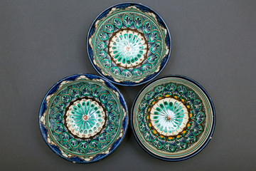 Ethnic Uzbek ceramic tableware on the gray background. Decorative ceramic cups with traditional uzbekistan ornament.