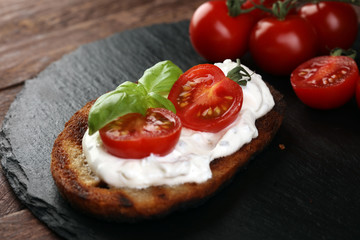 Bread with cream cheese and tomato for lunch table. Sharing antipasti on party or summer picnic time over wooden rustic background.