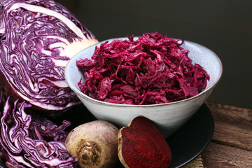 Shredded red cabbage in clay bowl on wooden background. Vegetarian healthy food.