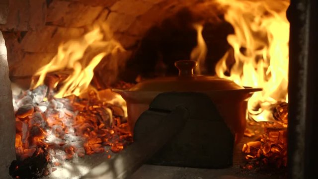 Cook puts pots of soup on a hot stove. Old Ukrainian authentic oven.