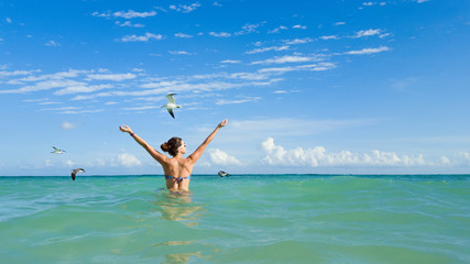 Joyful woman in bikini having fun on caribbean tropical vacation into the sea.