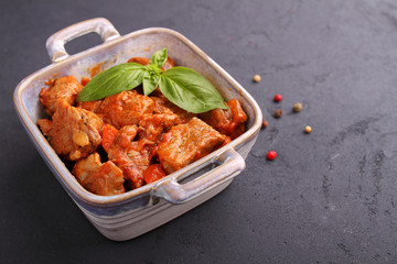 Ragout of meat with onions, carrots and tomatoes, decorated with basil,