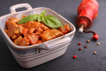 Ragout of meat with onions, carrots and tomatoes, decorated with basil,