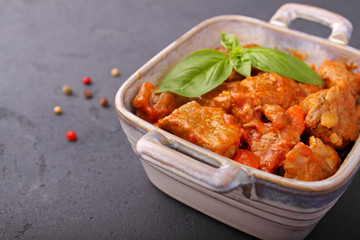Ragout of meat with onions, carrots and tomatoes, decorated with basil,