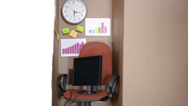 Simple small office in a cardboard box with computer desktop on white background tilt up